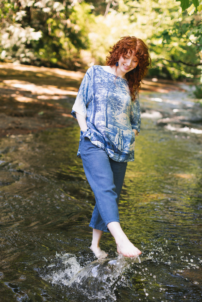 Model wearing Let the Light In bamboo viscose Luxe Tee shirt featuring print of Delft blue and white landscape pottery, and positive message of light and hope - Market of Stars