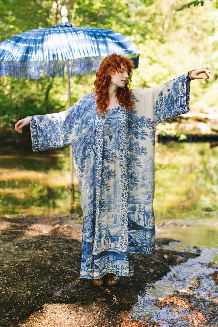 Model wearing Let the Light In long opera duster kimono featuring print of Delft blue and white landscape pottery, and positive message of light and hope - Market of Stars