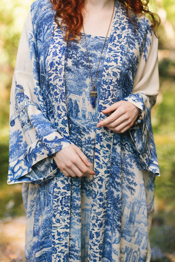 Model wearing Let the Light In long opera duster kimono featuring print of Delft blue and white landscape pottery, and positive message of light and hope - Market of Stars