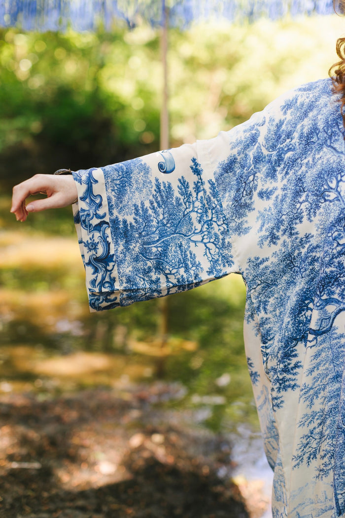 Model wearing Let the Light In long opera duster kimono featuring print of Delft blue and white landscape pottery, and positive message of light and hope - Market of Stars