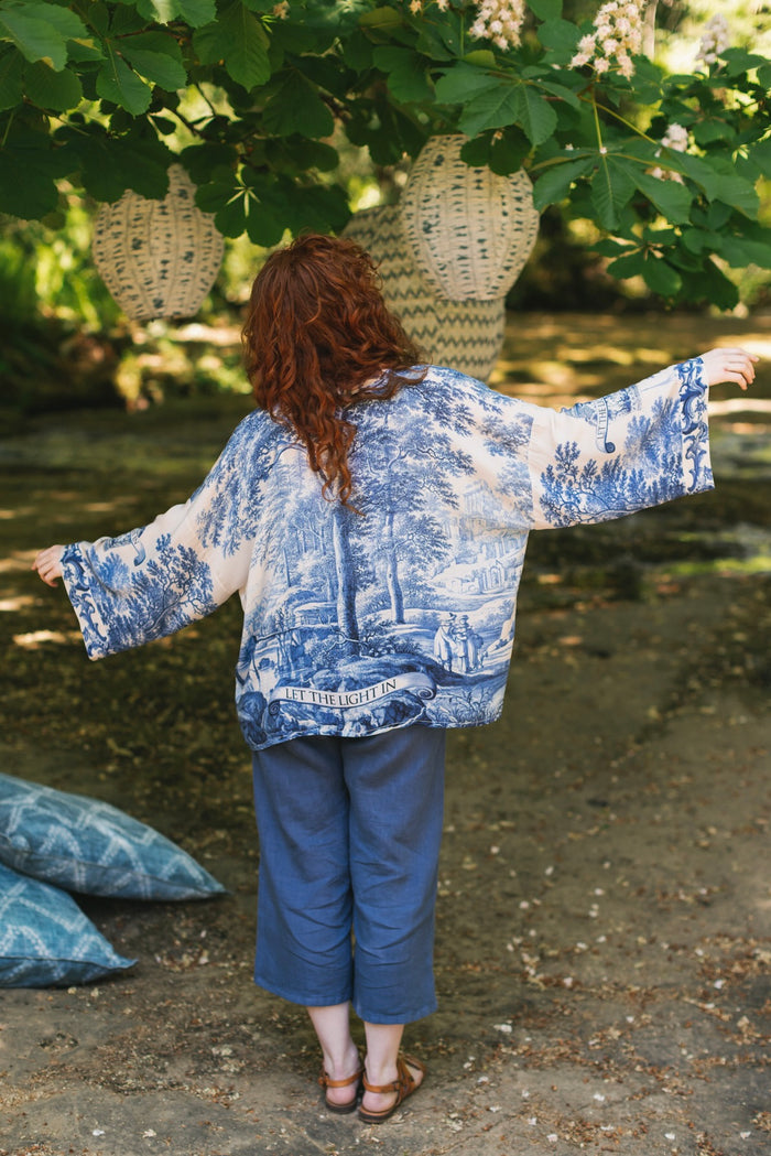 Model wearing Let the Light In cropped Pixie duster featuring print of Delft blue and white landscape pottery, and positive message of light and hope - Market of Stars