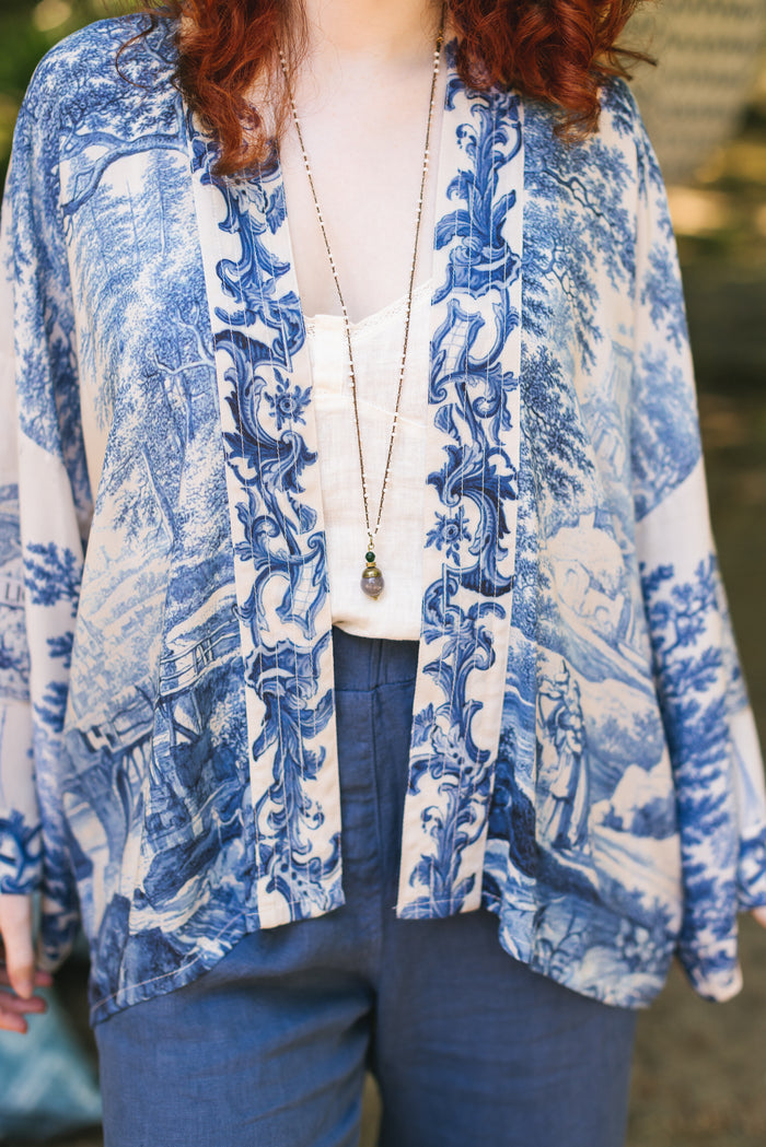Model wearing Let the Light In cropped Pixie duster featuring print of Delft blue and white landscape pottery, and positive message of light and hope - Market of Stars