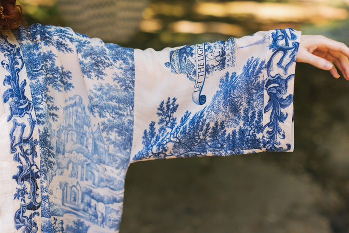 Model wearing Let the Light In cropped Pixie duster featuring print of Delft blue and white landscape pottery, and positive message of light and hope - Market of Stars