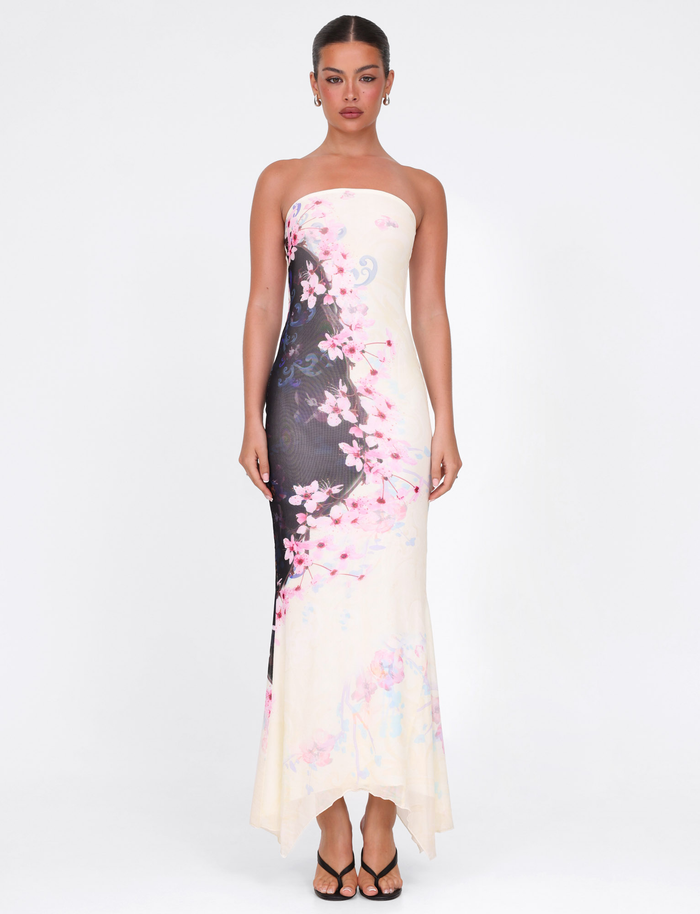 A woman faces forward in the TIGERMIST LILLIAN MAXI DRESS - MULTI: FLORAL: CHERRY BLOSSUM, her hair tied back and wearing black sandals, set against a plain white background.