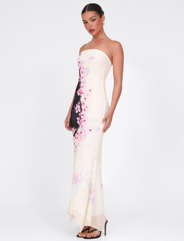 A woman poses against a white background in the TIGERMIST LILLIAN MAXI DRESS – MULTI: FLORAL: CHERRY BLOSSUM, a strapless mesh dress in pink and black tones, paired with black heeled sandals.