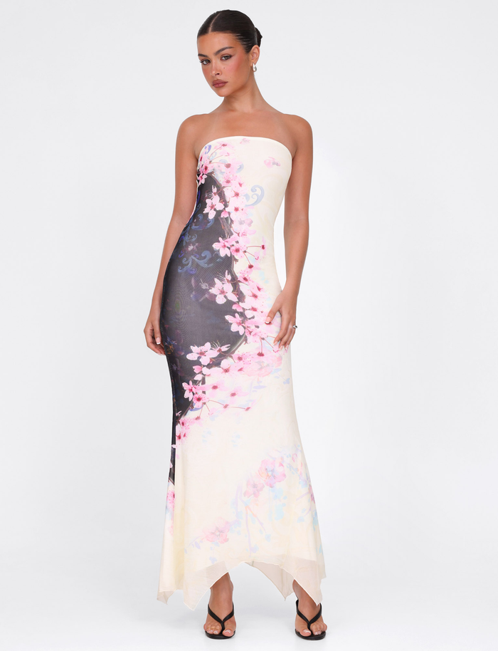 A woman stands against a white backdrop wearing the TIGERMIST LILLIAN MAXI DRESS in multi cherry blossom floral print, styled strapless with black strappy heels and her hands at her sides.