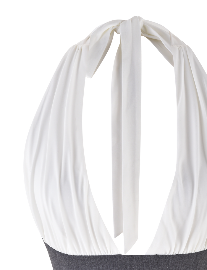 A close-up of the TIGERMIST LOTUS TOP - CREAM : GREY, featuring a large bow at the neck with draped fabric down the back, paired with a dark gray bottom.