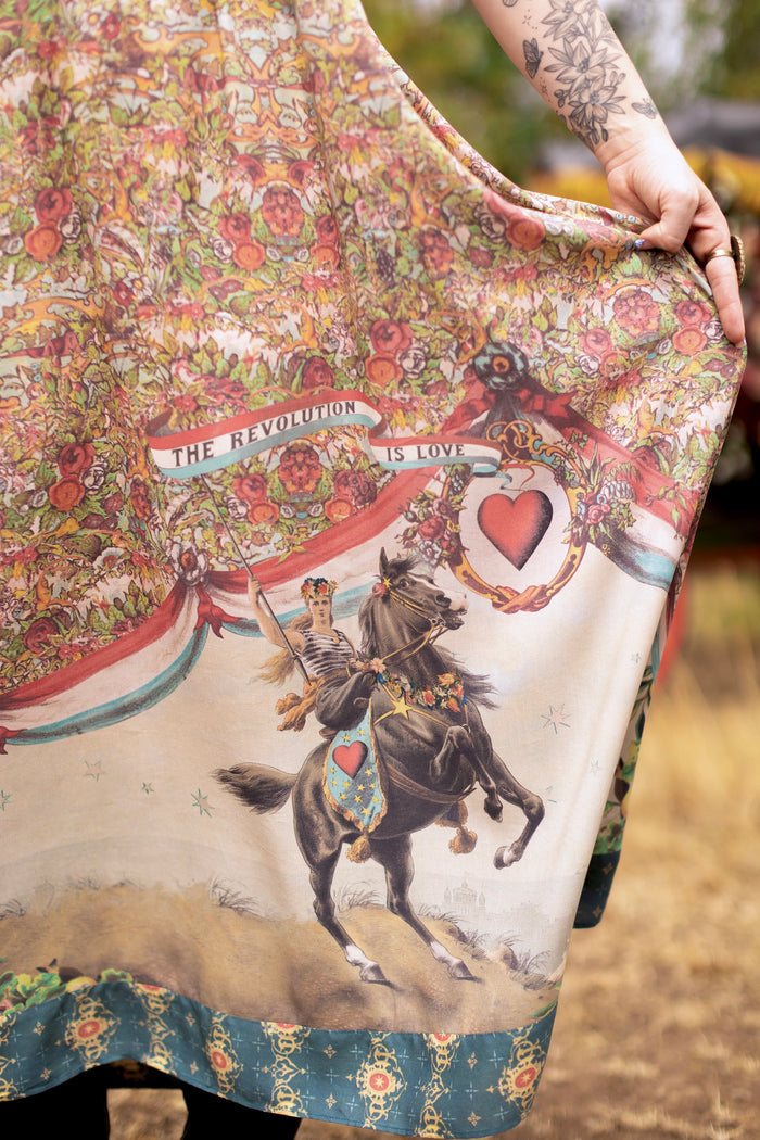 Model wearing a maxi-length slip dress ft. a woman astride a rearing horse, soft vintage florals, rosettes and lithographs from the 1800's - Market of Stars