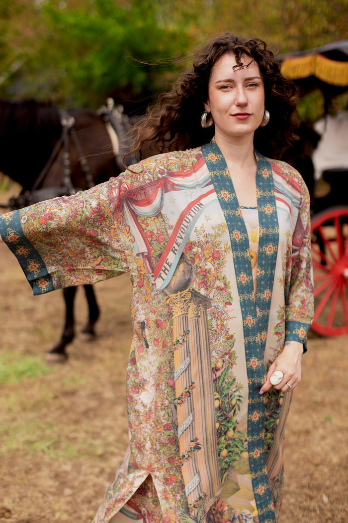 Model wearing a full-length duster ft. a woman astride a rearing horse, soft vintage florals, rosettes and lithographs from the 1800's - Market of Stars