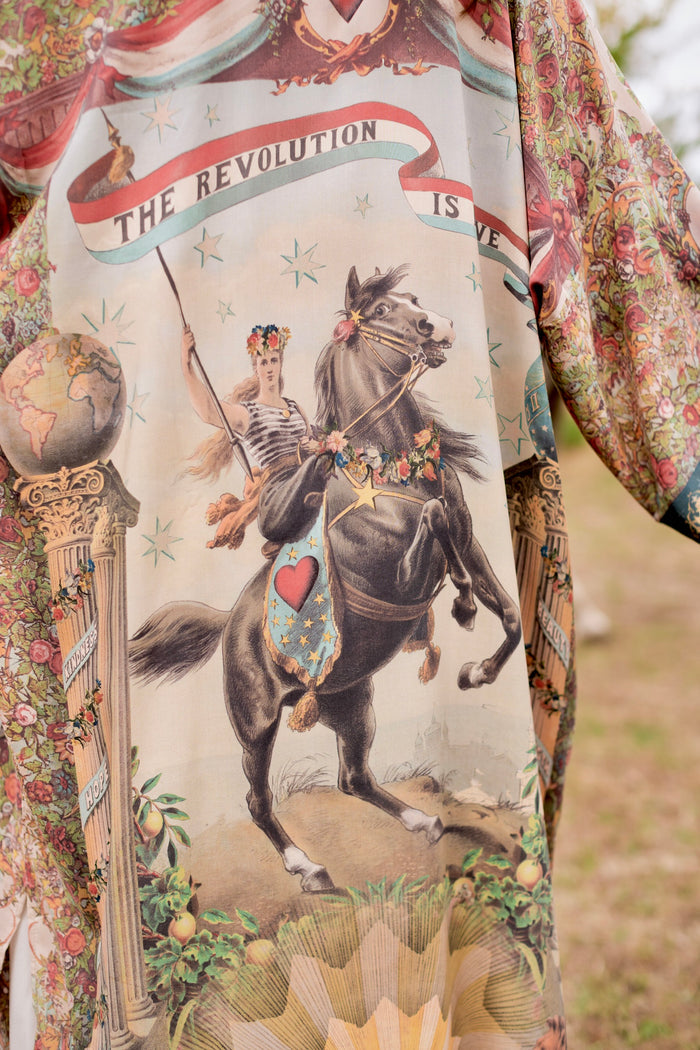 Model wearing a full-length duster ft. a woman astride a rearing horse, soft vintage florals, rosettes and lithographs from the 1800's - Market of Stars