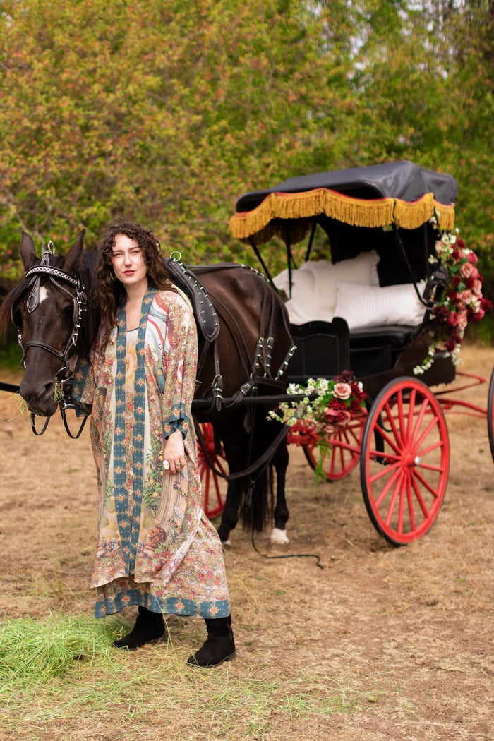 Model wearing a full-length duster ft. a woman astride a rearing horse, soft vintage florals, rosettes and lithographs from the 1800's - Market of Stars