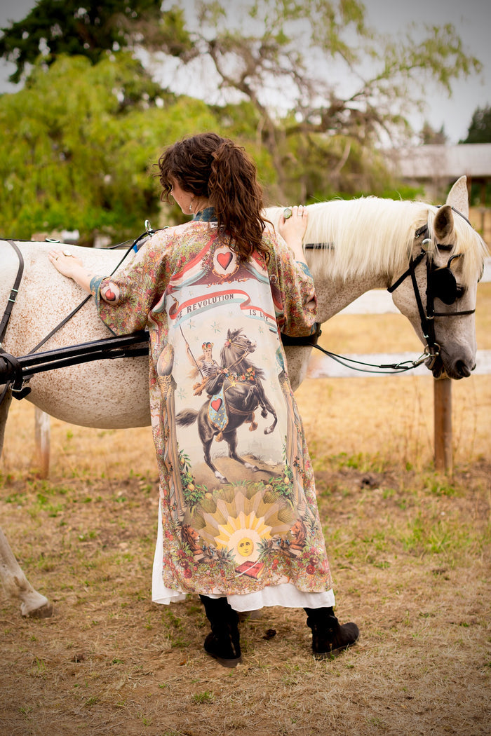 Model wearing a full-length duster ft. a woman astride a rearing horse, soft vintage florals, rosettes and lithographs from the 1800's - Market of Stars