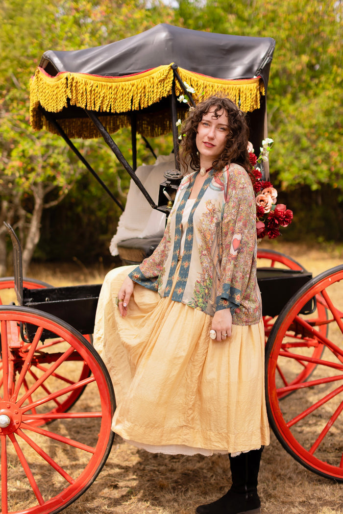 Model wearing cropped length duster ft. a woman astride a rearing horse, soft vintage florals, rosettes and lithographs from the 1800's - Market of Stars