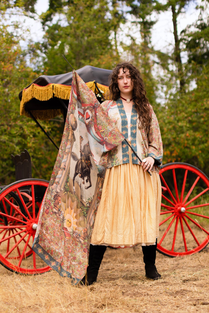 Model wearing a bamboo-viscose scarf ft. a woman astride a rearing horse, soft vintage florals, rosettes and lithographs from the 1800's - Market of Stars