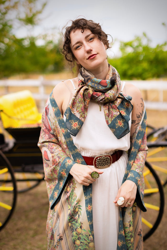 Model wearing a bamboo-viscose scarf ft. a woman astride a rearing horse, soft vintage florals, rosettes and lithographs from the 1800's - Market of Stars