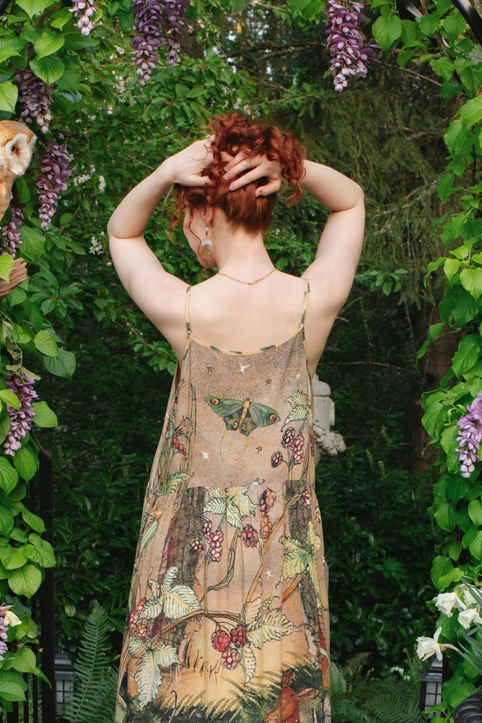 Model wearing an enchanting maxi-length slip dress featuring illustrations by Charles van Sandwyk, crafted from airy bamboo-based viscose with a touch of whimsical magic - Market of Stars