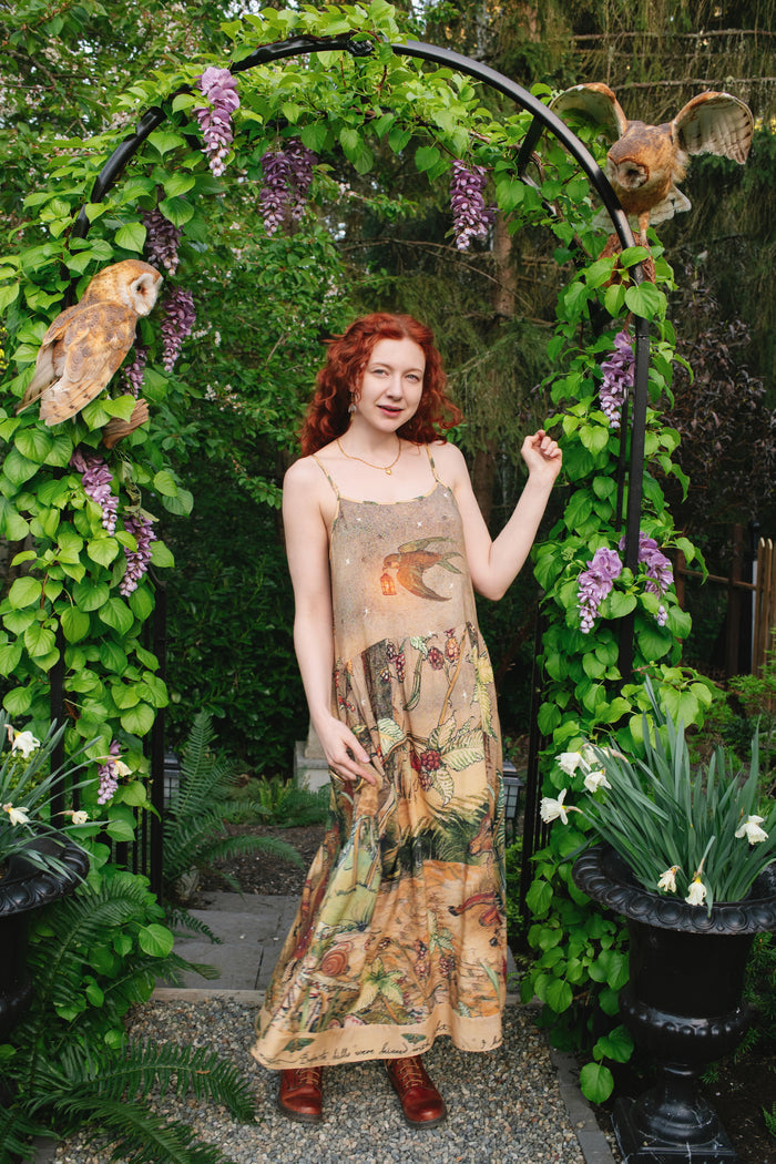 Model wearing an enchanting maxi-length slip dress featuring illustrations by Charles van Sandwyk, crafted from airy bamboo-based viscose with a touch of whimsical magic - Market of Stars