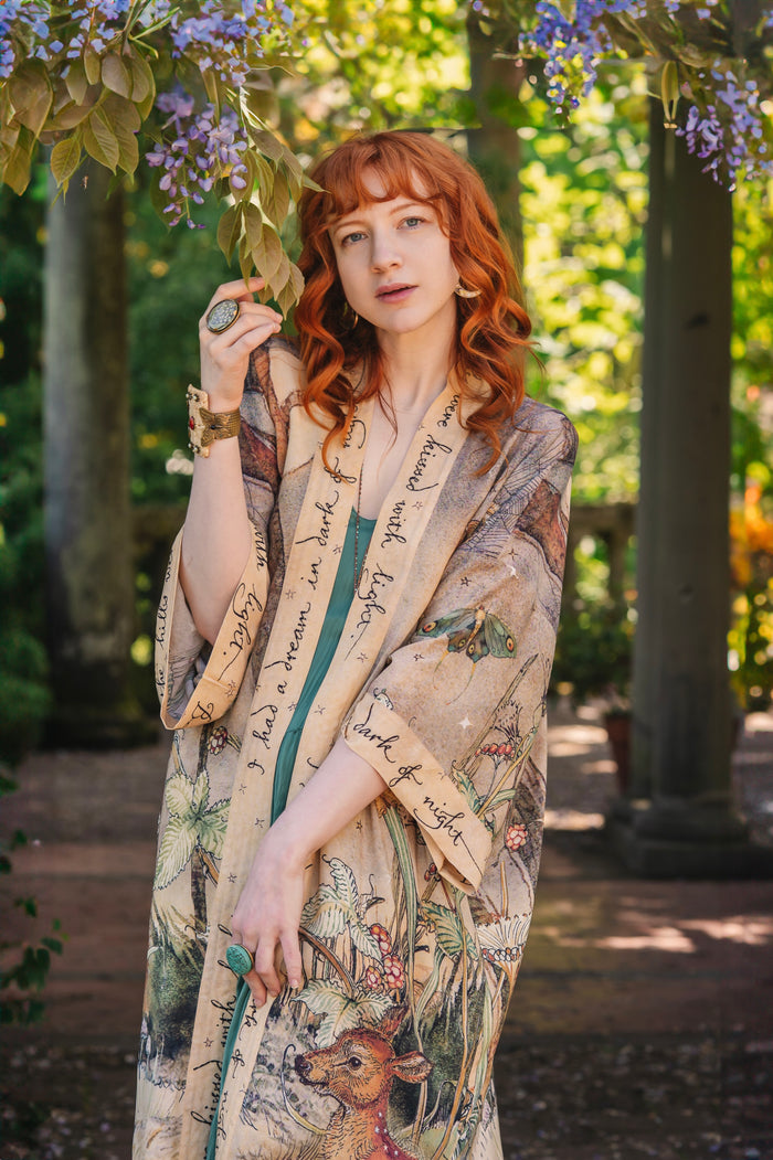 Model wearing an enchanting kimono duster robe featuring illustrations by Charles van Sandwyck's, crafted from airy bamboo-based viscose with a touch of whimsical magic - Market of Stars