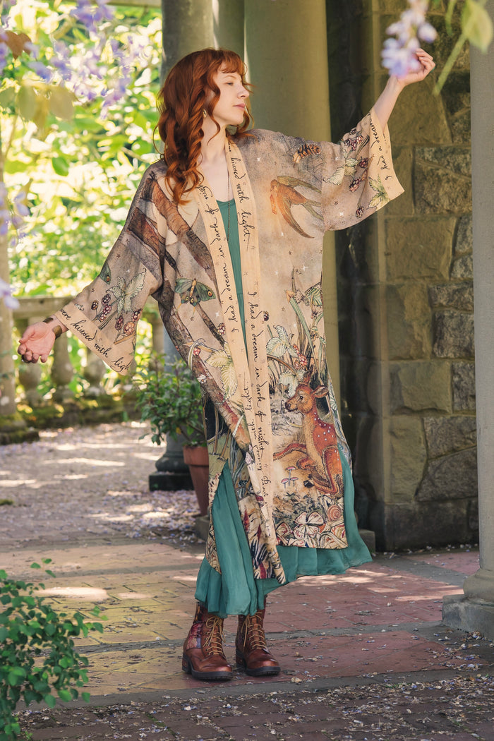 Model wearing an enchanting kimono duster robe featuring illustrations by Charles van Sandwyck's, crafted from airy bamboo-based viscose with a touch of whimsical magic - Market of Stars