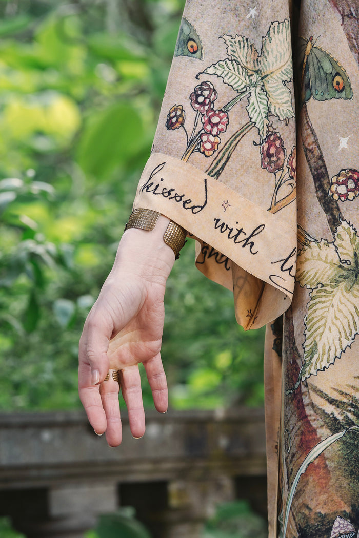 Model wearing an enchanting kimono duster robe featuring illustrations by Charles van Sandwyck's, crafted from airy bamboo-based viscose with a touch of whimsical magic - Market of Stars