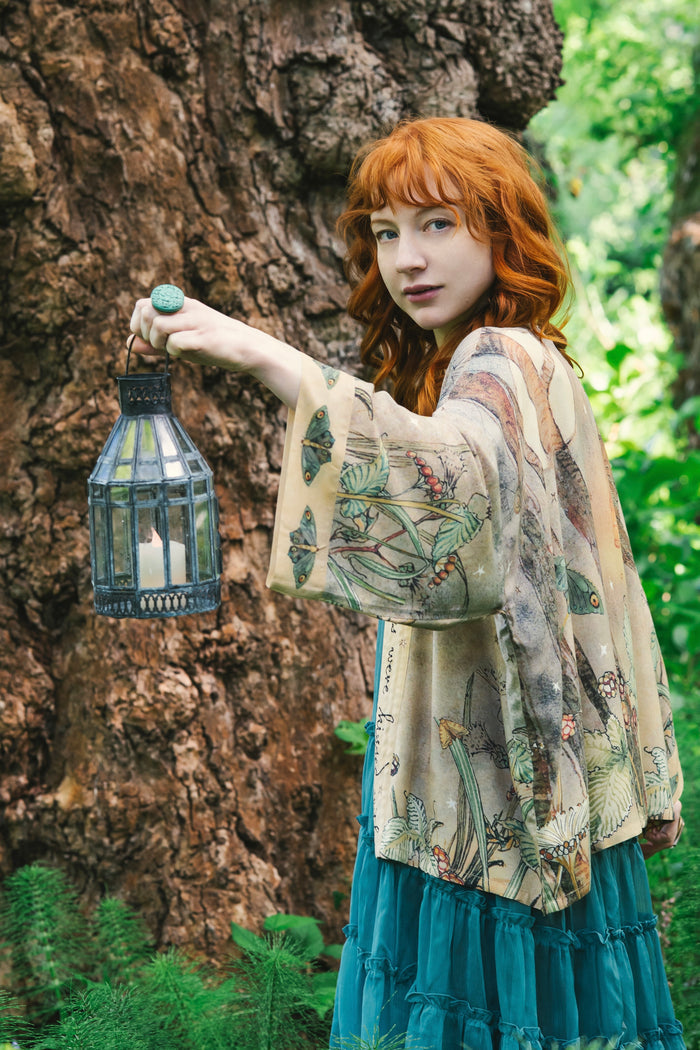 Model wearing an enchanting cropped kimono duster featuring illustrations by Charles van Sandwyck's, crafted from airy bamboo-based viscose with a touch of whimsical magic - Market of Stars