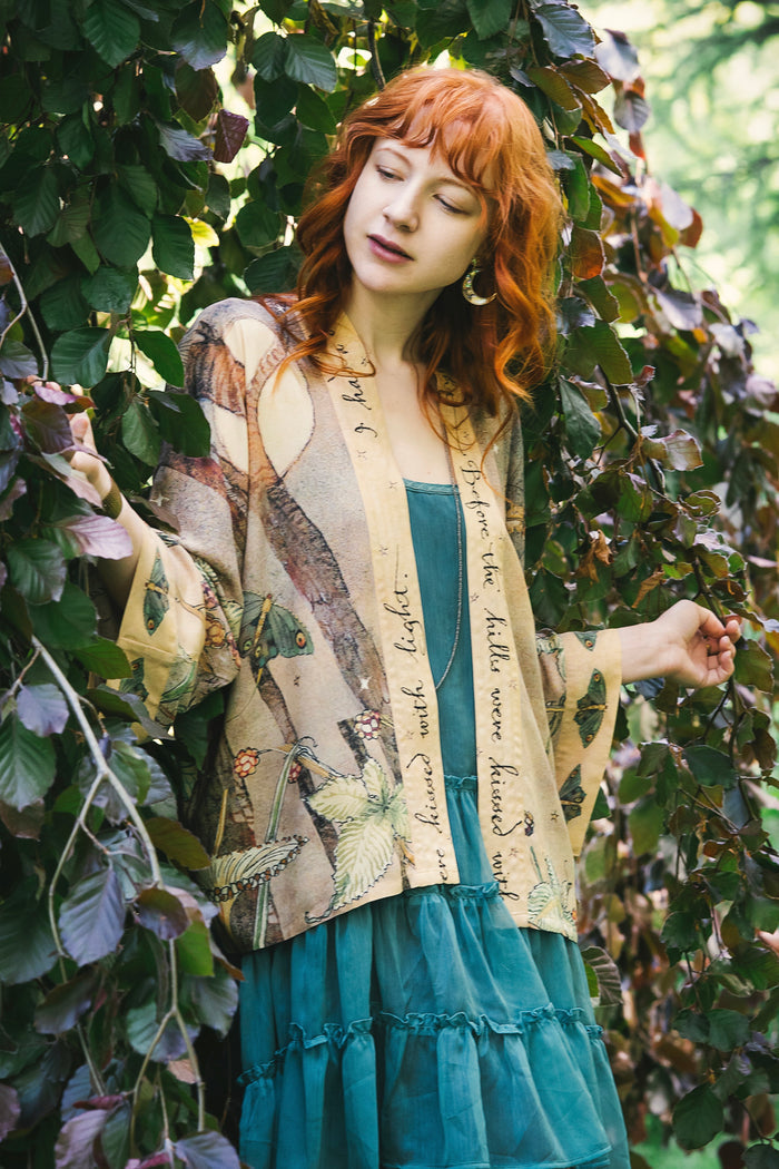 Model wearing an enchanting cropped kimono duster featuring illustrations by Charles van Sandwyck's, crafted from airy bamboo-based viscose with a touch of whimsical magic - Market of Stars