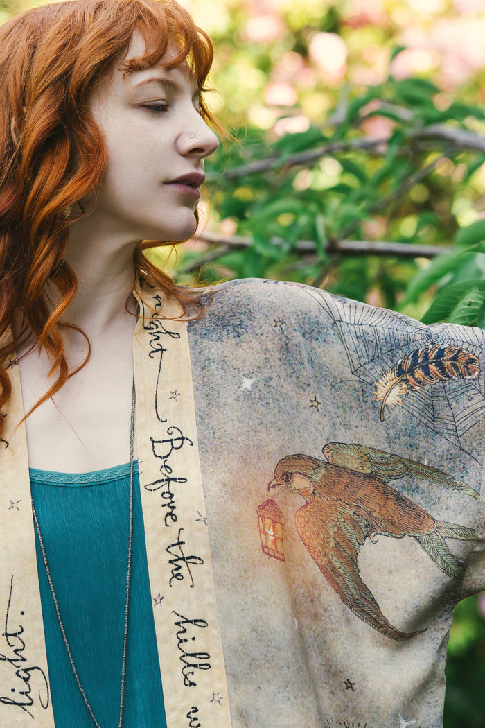 Model wearing an enchanting cropped kimono duster featuring illustrations by Charles van Sandwyck's, crafted from airy bamboo-based viscose with a touch of whimsical magic - Market of Stars