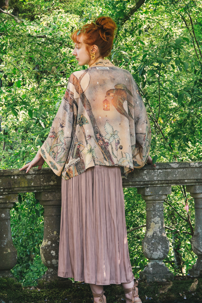 Model wearing an enchanting cropped kimono duster featuring illustrations by Charles van Sandwyck's, crafted from airy bamboo-based viscose with a touch of whimsical magic - Market of Stars