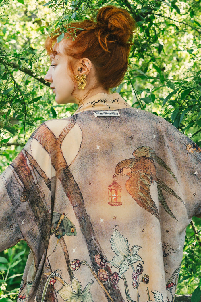 Model wearing an enchanting cropped kimono duster featuring illustrations by Charles van Sandwyck's, crafted from airy bamboo-based viscose with a touch of whimsical magic - Market of Stars