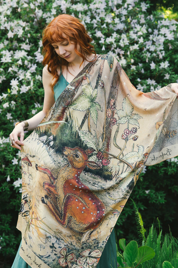 Model wearing an enchanting scarf featuring Charles van Sandwyck's illustrations, crafted from airy bamboo-based viscose with a touch of whimsical magic - Market of Stars