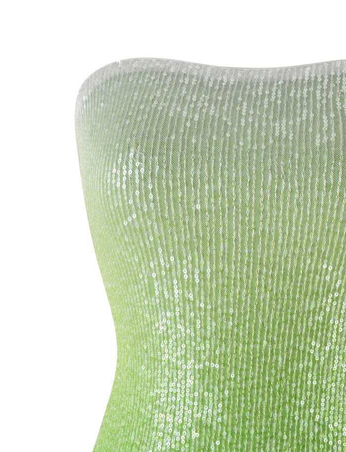 Close-up of the LYKA DRESS - GREEN : OMBRE : SEQUIN by TIGERMIST, showcasing its shimmering green ombre made with tightly packed sequins that create a sparkling effect. The gradient transitions smoothly from lighter at the top to darker towards the bottom, appearing to be stretched over a curved surface.