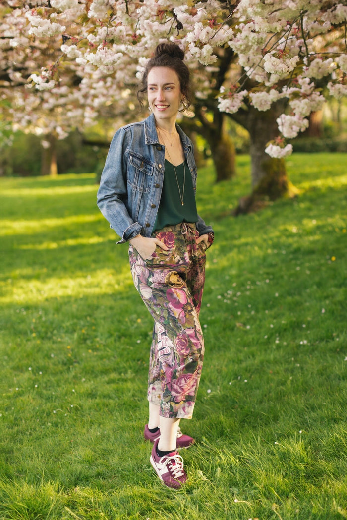 Model wearing linen blend artist pants featuring antique wishbone–Victorian coin–evening star–dandelion art and “Wish with Me” banner on floral background – Market of Stars