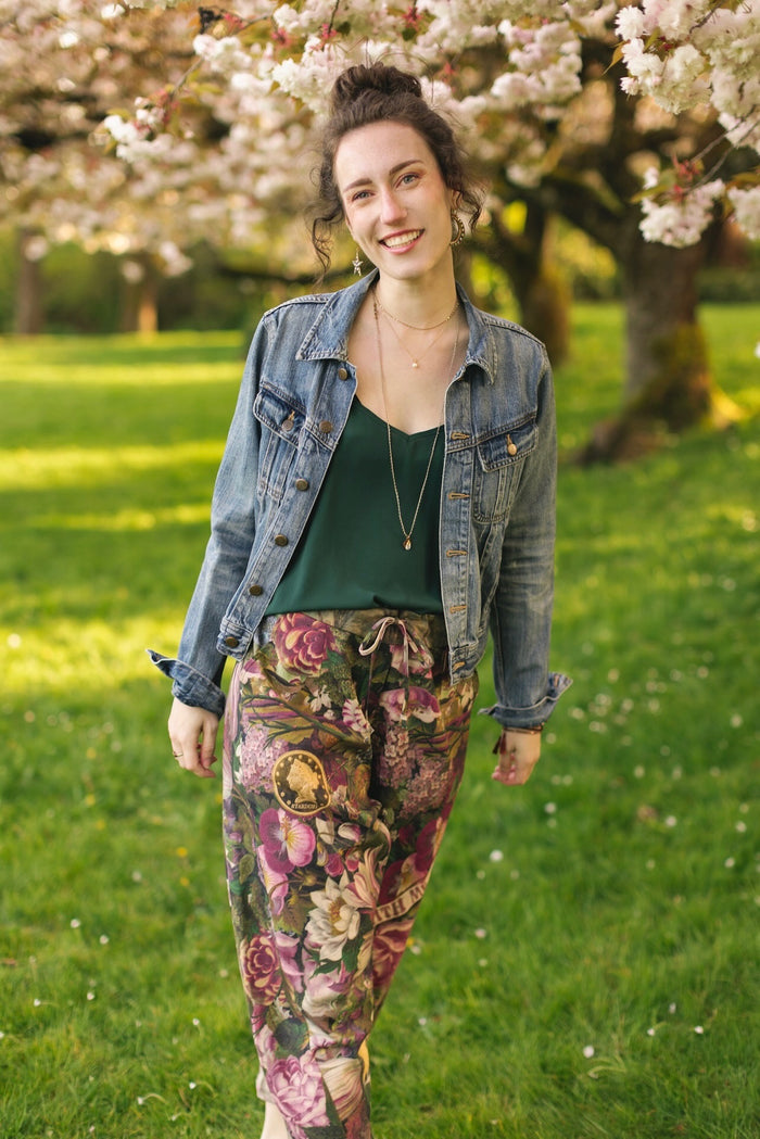 Model wearing linen blend artist pants featuring antique wishbone–Victorian coin–evening star–dandelion art and “Wish with Me” banner on floral background – Market of Stars
