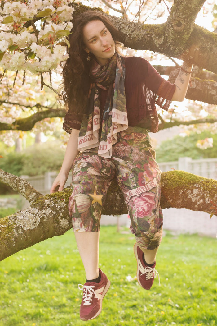 Model wearing linen blend artist pants featuring antique wishbone–Victorian coin–evening star–dandelion art and “Wish with Me” banner on floral background – Market of Stars