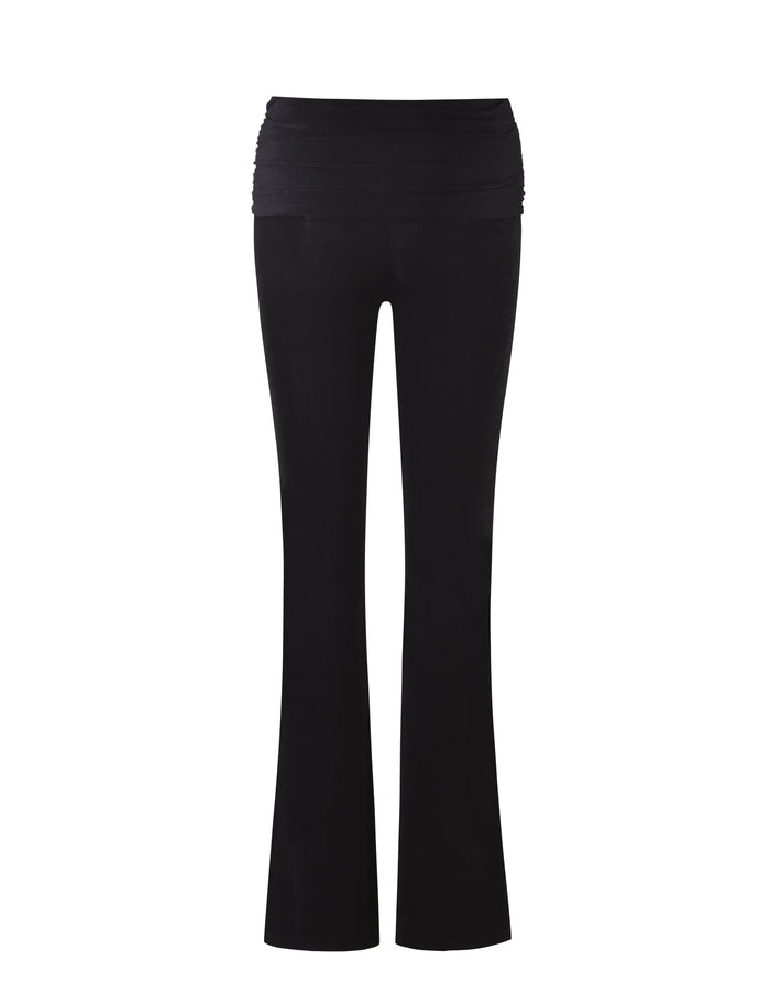 The MAKENA PANT - BLACK from TIGERMIST is shown against a white background. These women's yoga pants feature a high waist with a ruched band and flared legs. The material appears smooth and stretchy, making them ideal for exercise or casual wear.