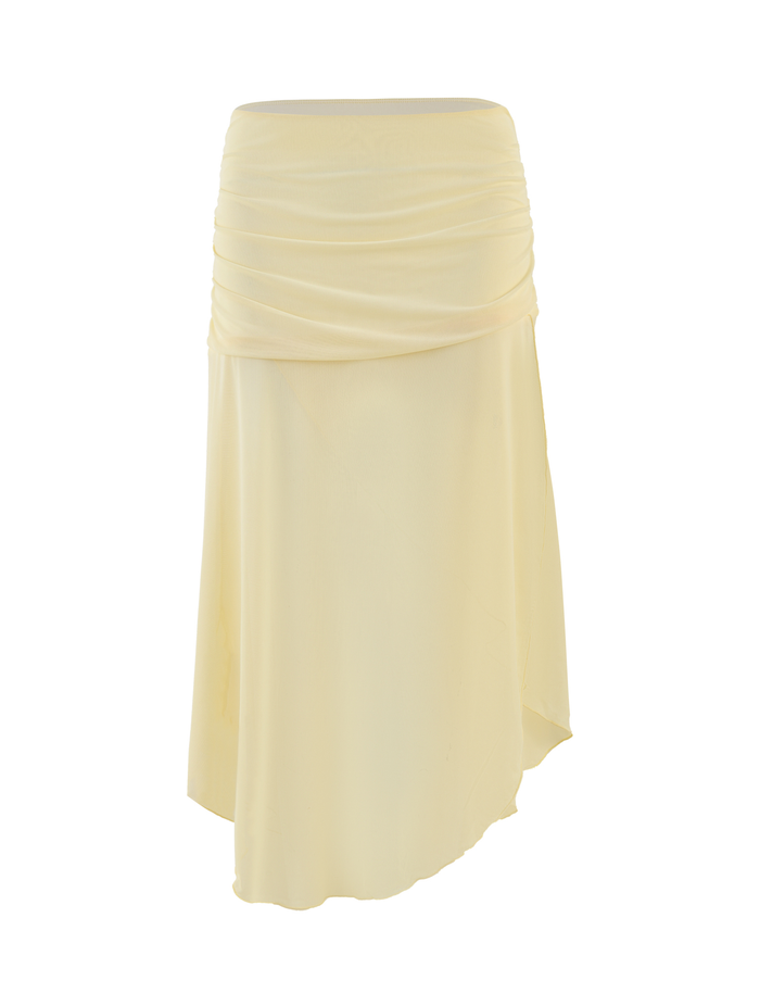 The TIGERMIST MARIANA SKIRT in pale yellow features an asymmetric wrap design with gentle ruching, a fitted waistband, knee-length cut, and uneven hem. Made from soft, slightly sheer mesh. Displayed on a plain white background.