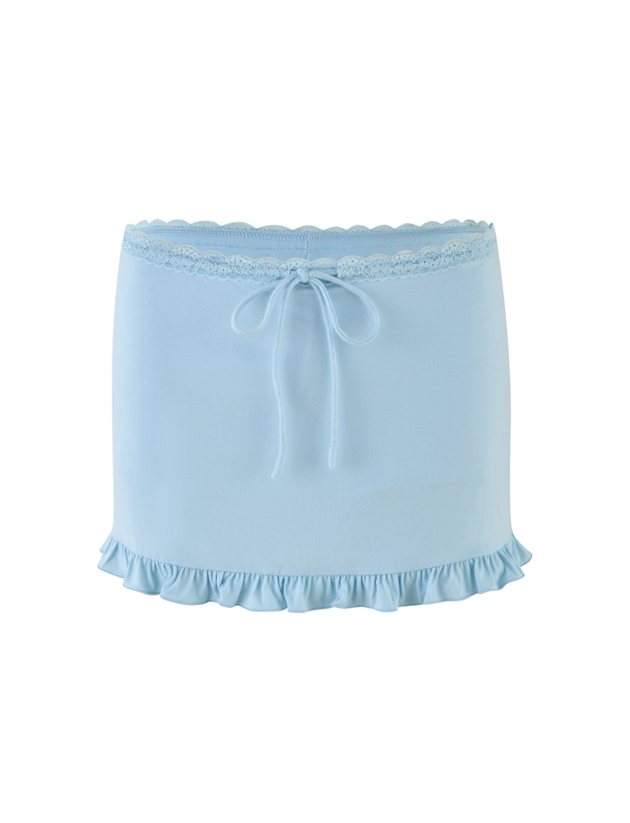 The MELLIE SKORT - BLUE by TIGERMIST is a baby blue mini skort in buttery jersey, featuring a ruffled hem, tonal lace at the top, and a center-front bow for a soft, feminine look.