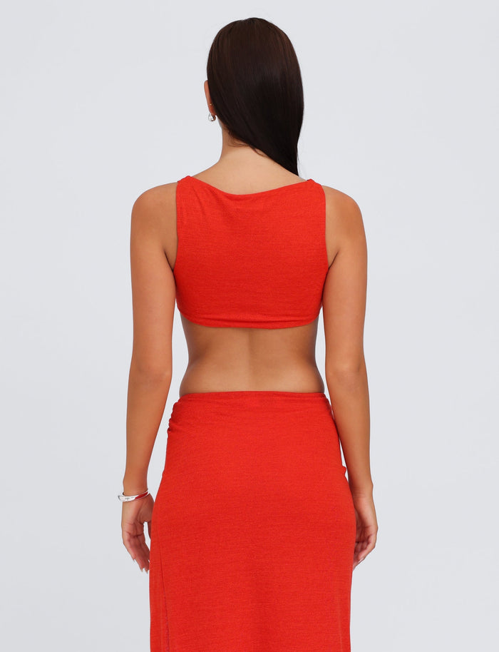 A person with long dark hair is standing with their back to the camera, wearing the TIGERMIST PAXTON TOP - RED : OMBRE, paired with a matching bodycon fit skirt. The background is a plain light color.