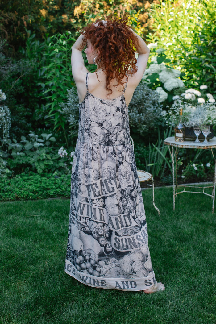 Model wearing Peace, Wine & Sunshine Bohéme Slip Dress featuring botanical collages and playful peace, wine and sunshine lettering on the hem – Market of Stars.