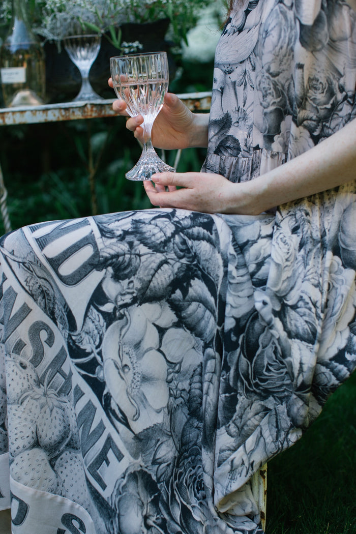 Model wearing Peace, Wine & Sunshine Bohéme Slip Dress featuring botanical collages and playful peace, wine and sunshine lettering on the hem – Market of Stars.