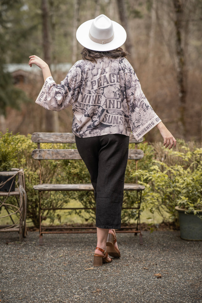 Model wearing Peace, Wine & Sunshine Bohéme Slip Dress featuring botanical collages and playful peace, wine and sunshine lettering on the hem – Market of Stars.