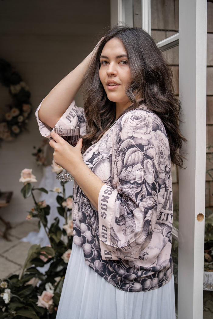 Model wearing Peace, Wine & Sunshine Bohéme Slip Dress featuring botanical collages and playful peace, wine and sunshine lettering on the hem – Market of Stars.