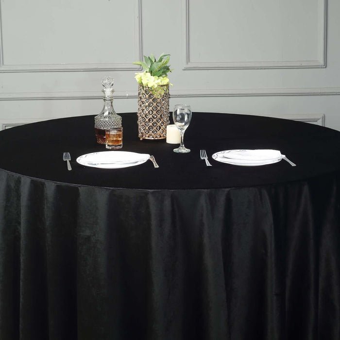 Elegant black table setting with plates, glassware, and decorative vase.