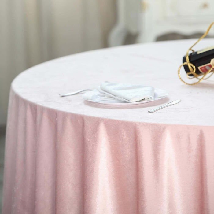 Elegant pink tablecloth draping over a round table with napkin and plate.