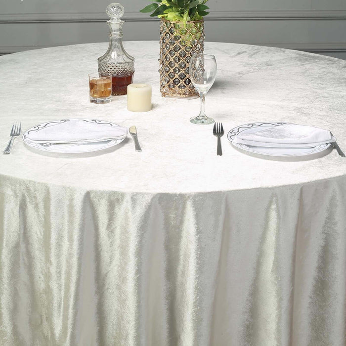 Elegant dining setup with a round table, plates, glasses, and decorative elements.