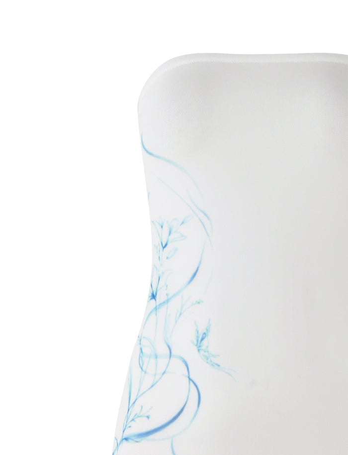 Close-up of the ROMINA MESH DRESS - WHITE from TIGERMIST, a strapless design adorned with delicate blue floral designs. This fitted dress showcases the floral pattern concentrated on one side, enhancing its minimalistic and elegant appearance. Only the upper part of the dress is visible in the image.