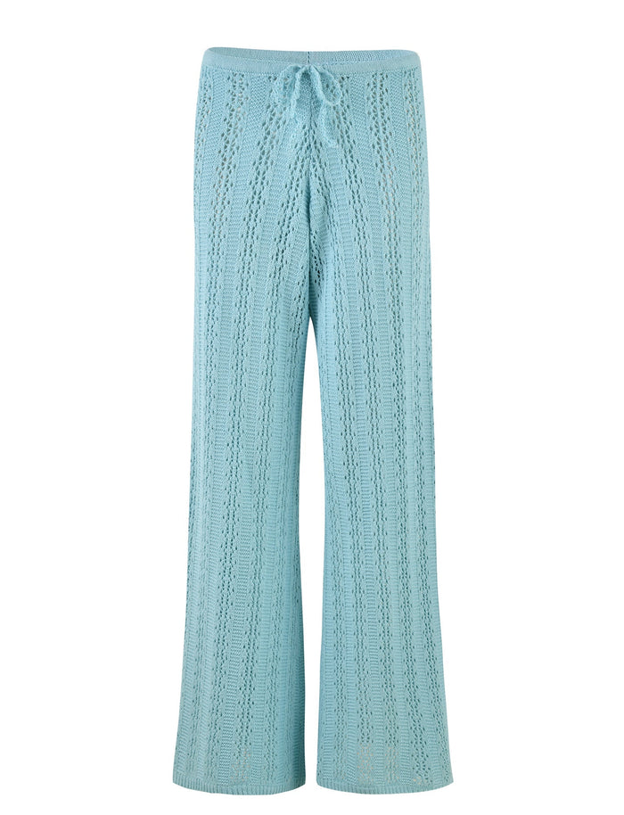 A pair of light blue crochet pants, the SANDOR PANT - BLUE : BABY BLUE from TIGERMIST, with a drawstring waist. These pants feature a detailed, lace-like pattern and a wide-leg design, offering a relaxed and airy appearance.
