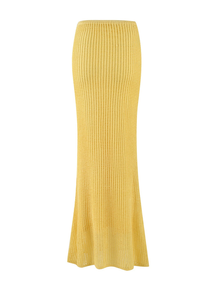 The SHAH SKIRT - YELLOW : LEMON by TIGERMIST is a maxi length, high-waisted yellow crochet skirt that boasts a straight cut with a flared bottom. Its ribbed texture and semi-transparent design offer a light and airy appearance, making it perfect for warm weather.
