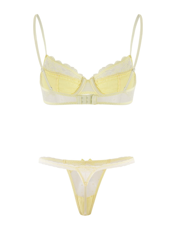 The SHAI SET - YELLOW : LEMON by TIGERMIST includes a light yellow lingerie set featuring a bra with adjustable shoulder straps and lace accents, paired with a matching thong. The bra has underwire cups and a clasp at the back, while the thong is designed with delicate lace trim, creating an elegant and delicate look.