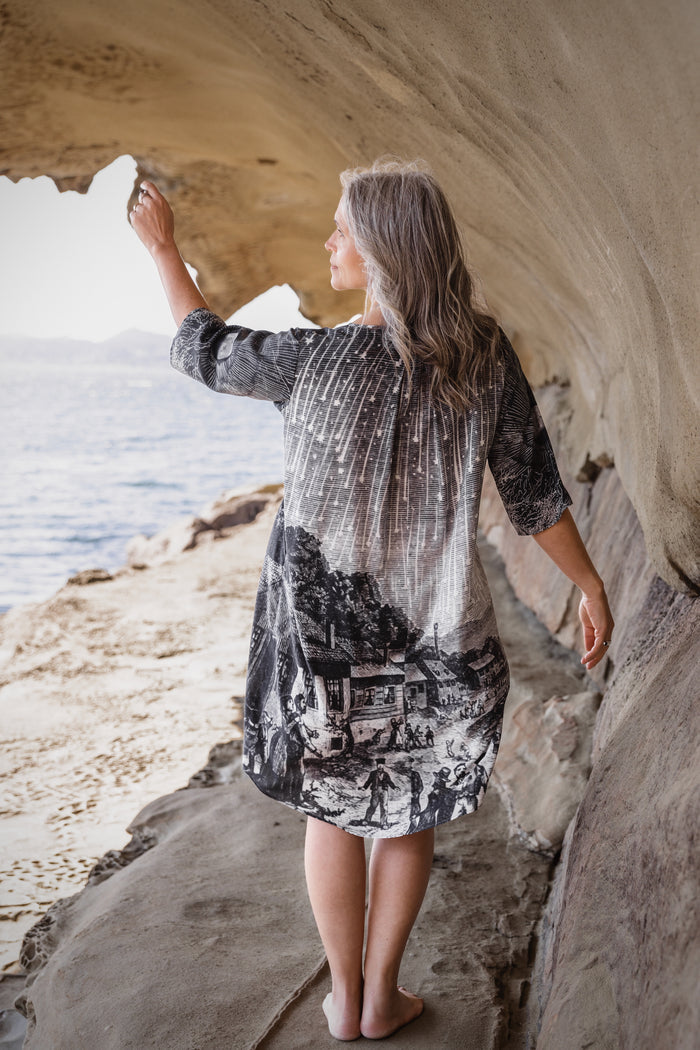 Model wearing a celestial knee-length artist dress in bamboo & wood blend viscose ft. the 1833 Leonid meteor shower in a dreamy star-filled night sky - Market of Stars.